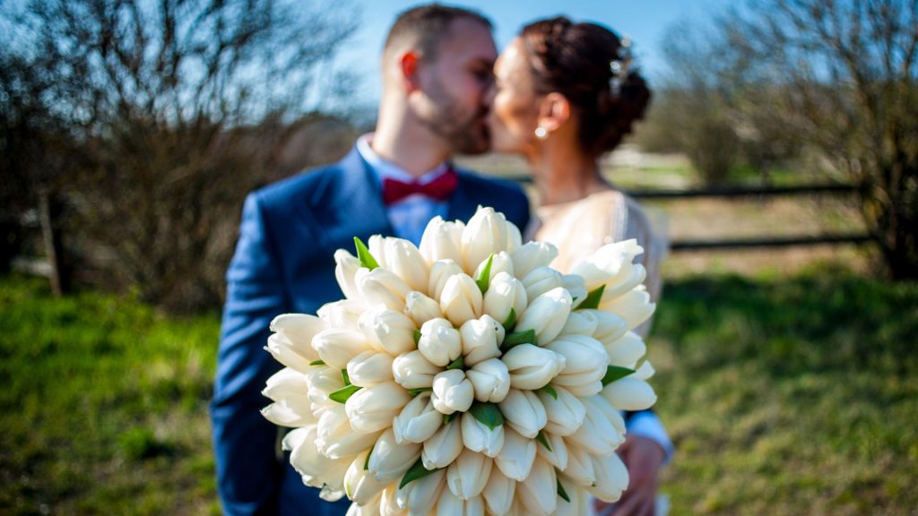 Esküvői csokor fehér tulipánokkal, pár csókolózik