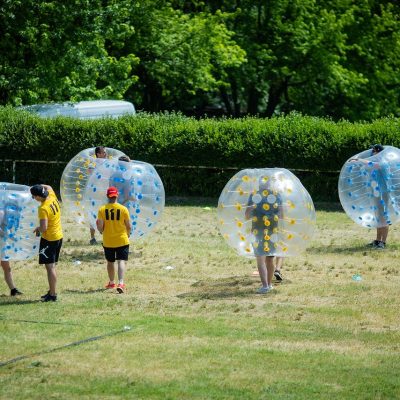 Bubble football players in inflatable balls on grass