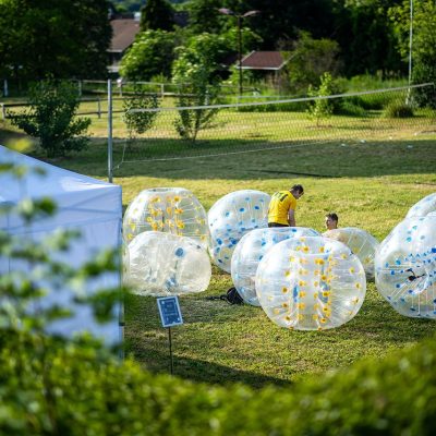 Bubble football activity with inflatable balls on grass.